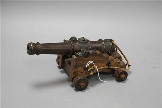 An early 20th century bronze model of a Naval cannon, on wooden trunnion base, length 25cm